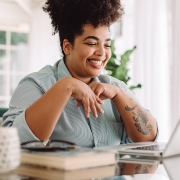 Woman with laptop in living room attending telehealth psychology session