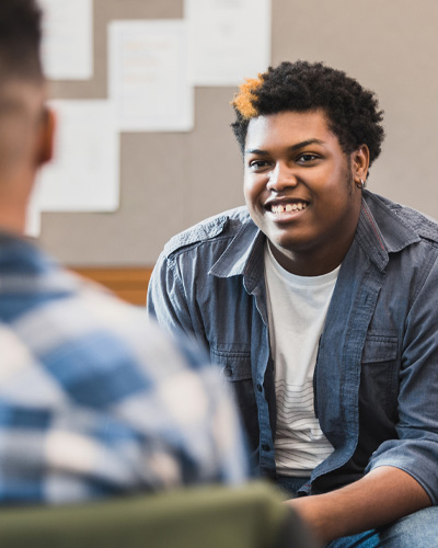 Young man talking to psychologist or therapist in foreground