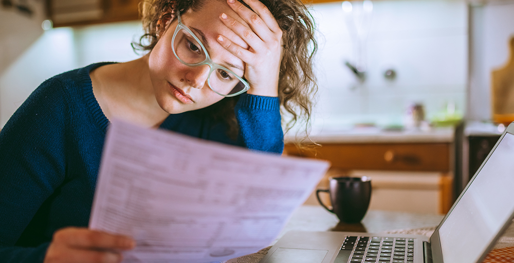 Woman looking at bills rubbing her head