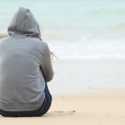 Woman in hoodie sitting on the beach on a winter morning