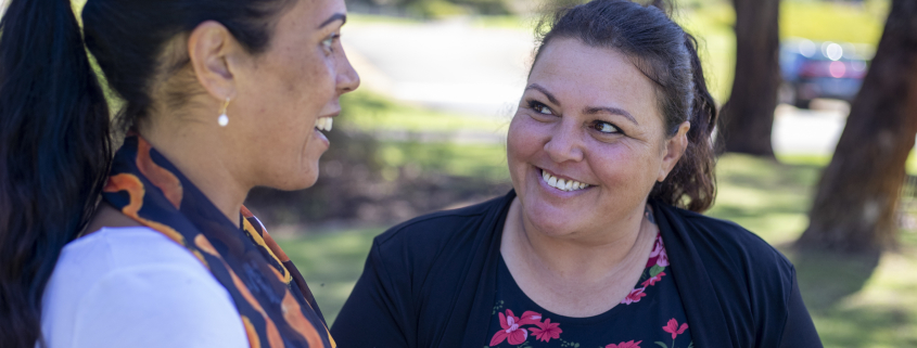 Woman talking to another woman in a sunny park outside