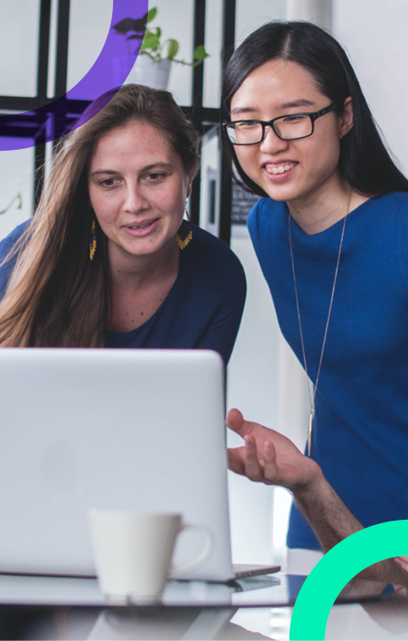 Two women dressed in blue looking at information on a laptop screen