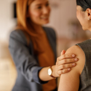 Two women facing each other. One woman reassures the other with her hand on her arm.a Two women facing each other. One woman reassures the other with her hand on her arm.a