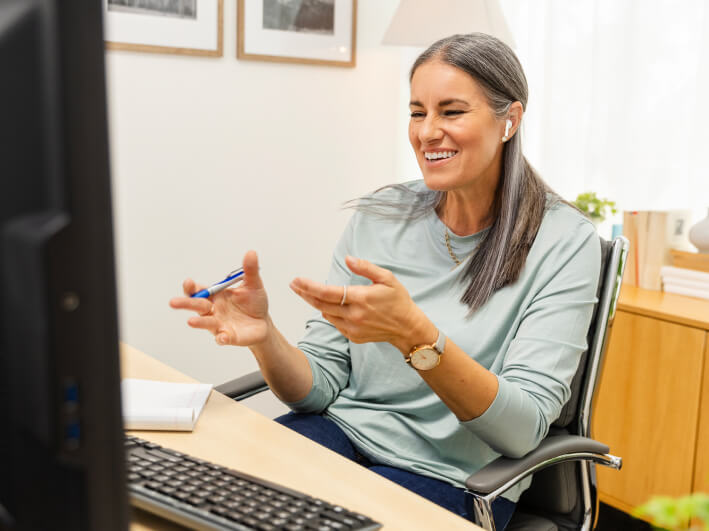 Smiling lady gesturing at her computer screen
