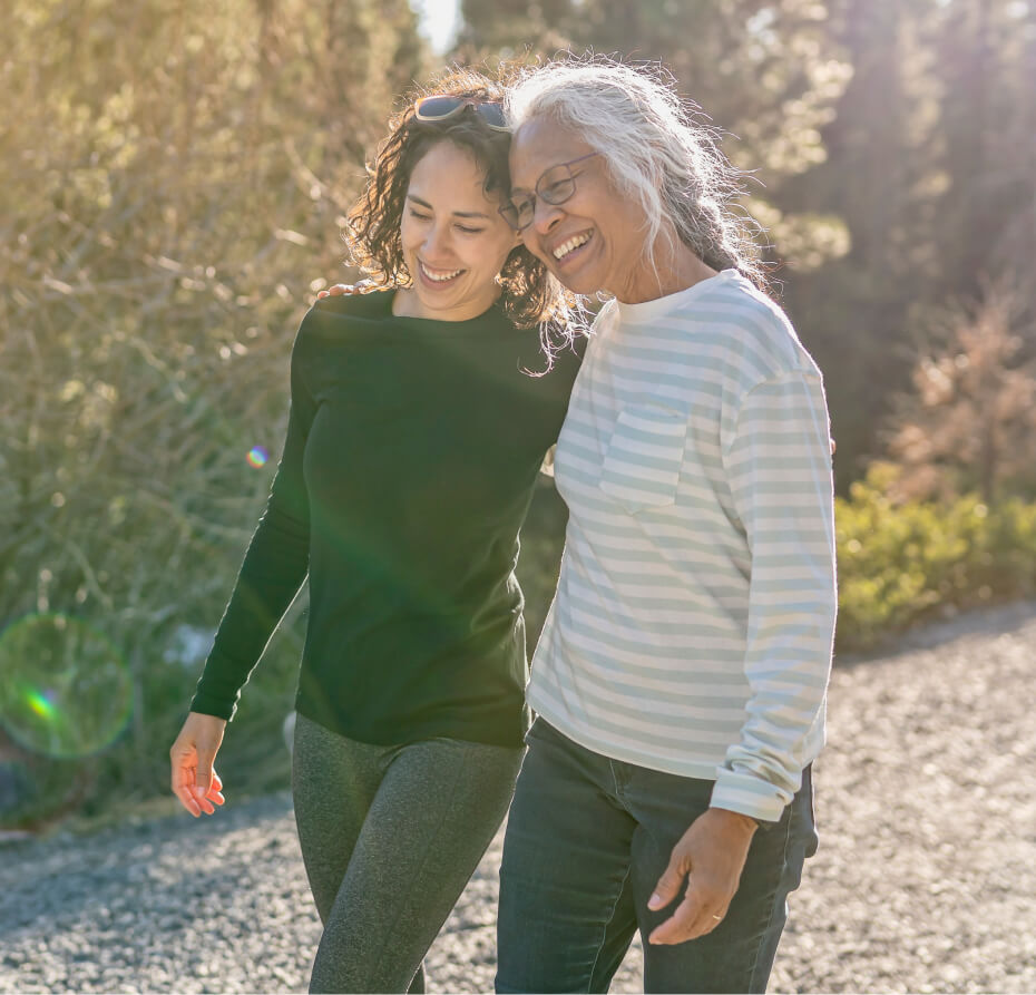 Two women walking and smiling with their arms around each other